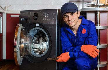 Young smiling happy man plumber handyman in blue overalls