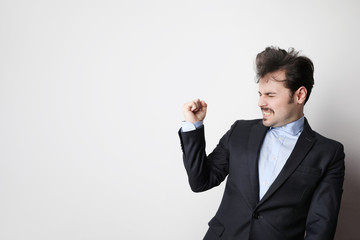 Shot of young businessman wearing suit and blue shirt with success gesture. Free space for text.