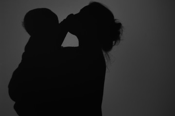 Silhouette Of Happy Mother and Baby. Mom kissing baby, Happy Mother's Day concept