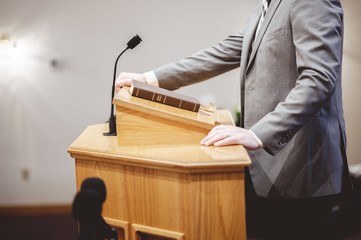Selective focus shot of a male standing and speaking from the pulpit - obrazy, fototapety, plakaty