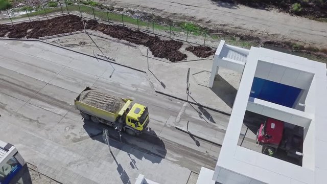 a yellow truck loaded with sand, pulls up to a checkpoint. Freight transportation. Construction work at a closed facility. Logistic work.