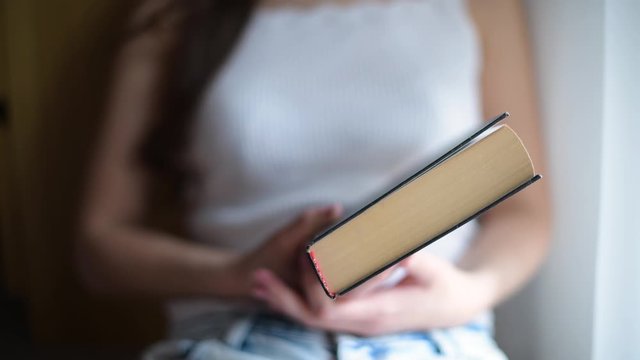 girl closes the book she has read, close-up of the end of the book, the girl s face is not visible, selective focus