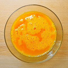 Blending mix of hen eggs in transparent bowl on the kitchen table
