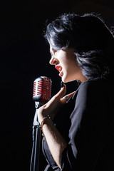 Gorgeous vintage 1950s lady with microphone in a black dress....