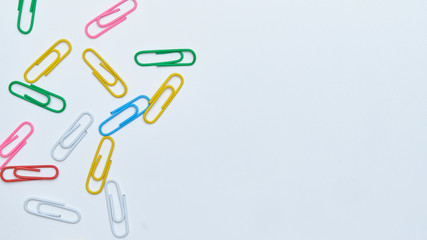 Multi-colored paper clips on a white background. Top view. Copy space.