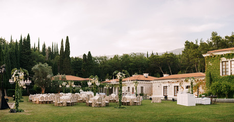 Wedding dinner table reception. Elegant tables for guests with cream tablecloths with patterns, on...