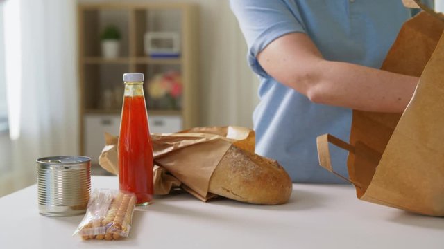 health protection, safety and pandemic concept - close up of woman in protective medical gloves taking food from paper bag at home