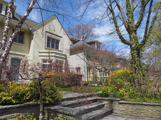 Street of large traditional detached homes with front yards with spring flowers