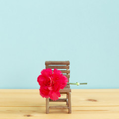 Pink spray carnation flower on empty chair. Teacher's day concept, copy space