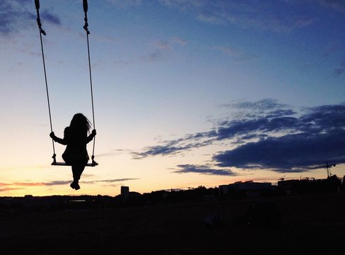 Silhouette Woman Swinging Against Sky During Sunset