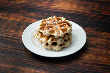 belgian waffle over a white plate with sugar
