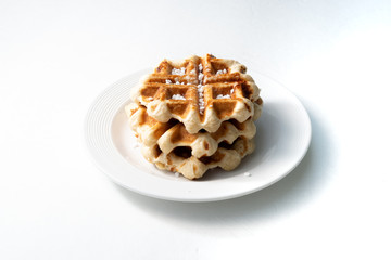 belgian waffle over a white plate with sugar