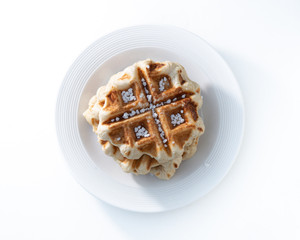 belgian waffle over a white plate with sugar