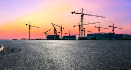 Empty asphalt road and construction site landscape at sunrise.