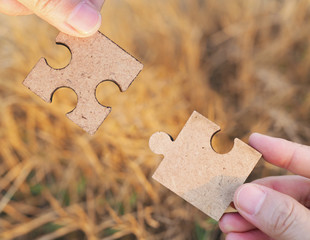 Two hands trying to connect couple puzzle piece with nature background. symbol of association and connection. business strategy.