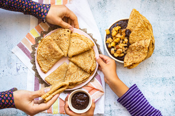 Family eat breakfast - homemade french crepes or thin pancakes together. Hands hold sweet vegan dessert.