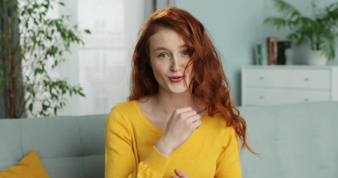 Cheerful pretty young Caucasian woman blogger talking to camera and telling something from home. Self-isolation lockdown concept. Beautiful internet coach having videoblog. Vlog concept. Coaching.