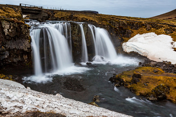Fototapeta na wymiar Kirkjufellsfoss waterfalls surrounded by melting snow in February