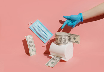 Creative concept of the economic crisis of 2020, monetary inflation during the coronavirus. The photo shows dollars, toilet paper, a medical mask and protective gloves.