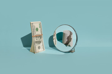 A pack of dollars is standing in front of the mirror. Mirror reflection of empty paper. The concept of inflation and crisis during the coronavirus
