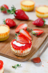 Mini strawberry cheesecake on a bamboo cutting board.