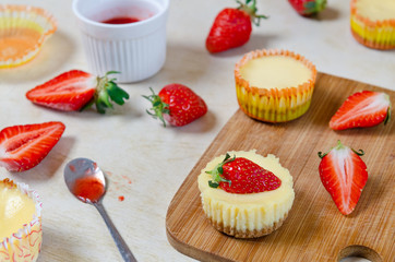 Mini strawberry cheesecake on a bamboo cutting board.