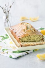 A close up view of a Lemon Poppy seed bread loaf against a sunny window.
