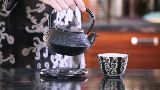 Women's hands pouring tea from a teapot