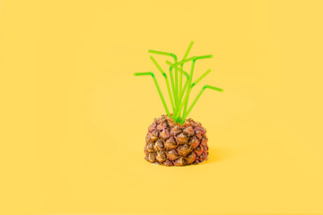 Pineapple on a yellow background with a straw. Creative concept summer drinks and juice