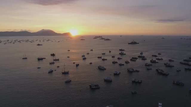 Drone flying in reverse from a beautiful sunset over the Pacific Ocean and you can see boats in a calm ocean in the middle of a warm summer afternoon.