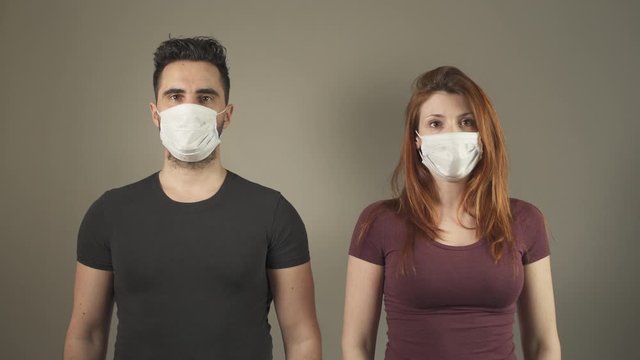 Young couple with surgical Masks, standing and facing at camera in studio, during covid-19 pandemic virus in France. 4K UHD. Two persons. Disease Prevention. Social Distance in relationship.