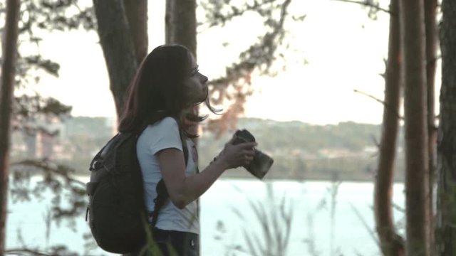 Beautiful girl takes picture on dslr camera. Blogger creates content. Traveler photographing scenic view in forest. Girl take photo video on mirrorless camera