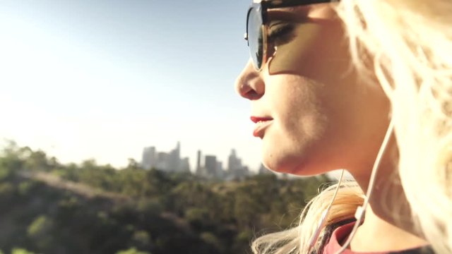 Girl Puts On Sunglasses, Cityscape Background