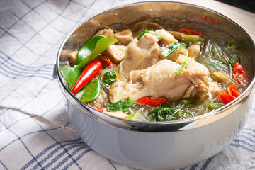 Homemade chicken and vegetable soup with glass noodles In the cup on the wooden background. Spicy ingredients thai food.