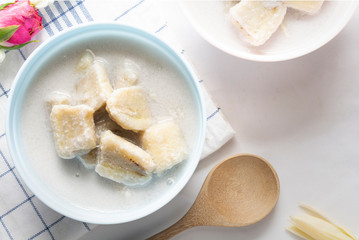 Banana in coconut milk on a vintage blue cup and white cloth background. Traditional sweet dessert of asian, Thailand.