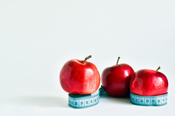 diet, healthy eating, food and weight loss. measuring tape wrapped around red apples