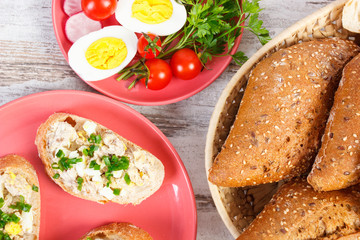Slice of baguette with fish paste, egg, tomato, radish and fresh rolls