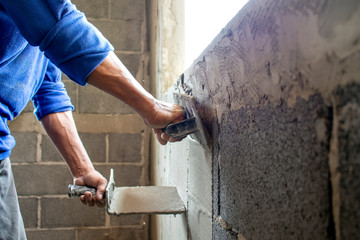 Construction workers use plaster trowel to build cement walls, house building ideas, and interior extensions.
