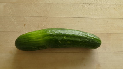  a wooden background lies a fresh cucumber