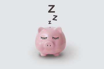 Pink piggy bank pictured sleeping on gray background