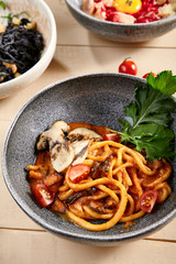 Pichi with mushrooms and creamy tomato allione in gray bowl