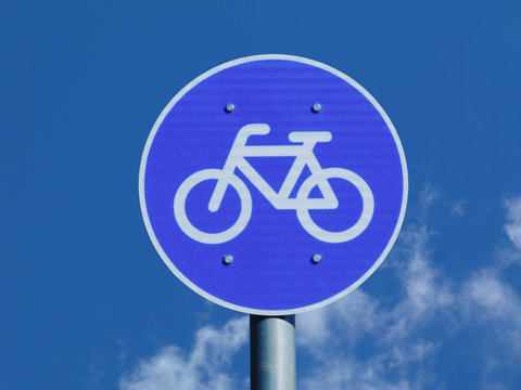 bicycle path and route road and traffic sign. bicycle icon depicting dedicated bicycle cycling lane. blue sky background. circular metal plate with white border. sports and recreation concept