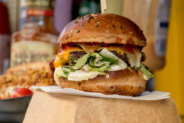Fresh melting burger ready to eat during fast food festival. Outdoor catering event, brunch