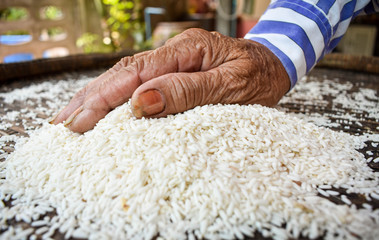 White rice on a wooden background and farmers are drying rice outdoors. 

