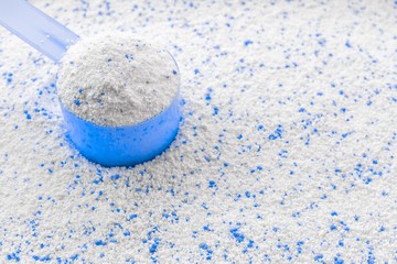 Detergent background. White wash powder with cup for laundry, washing machine. Soap clean texture with scoop. Dry cleaning, Chores of housewife concept. Regular washing.