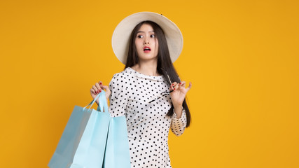 Asian pretty young woman  on yellow colour background. She smiling and  happy shopping bags. she nice-looking lovely attractive shine .Summer Sale colourful happy time.