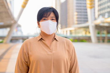 Overweight Asian woman with mask at skywalk bridge