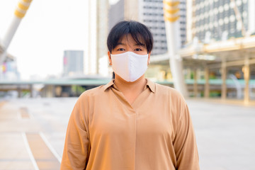 Overweight Asian woman with mask for protection from corona virus outbreak at skywalk bridge