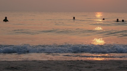 Silhouette of blurry people swimming in the sea on golden beautiful summer sunset 