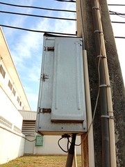 Electrical metal box on posts isolated on ground field and blue sky background closeup. In Samut Sakhon, Thailand.